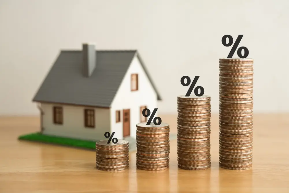 Stack coins as graph trend up and interest rates with house model background